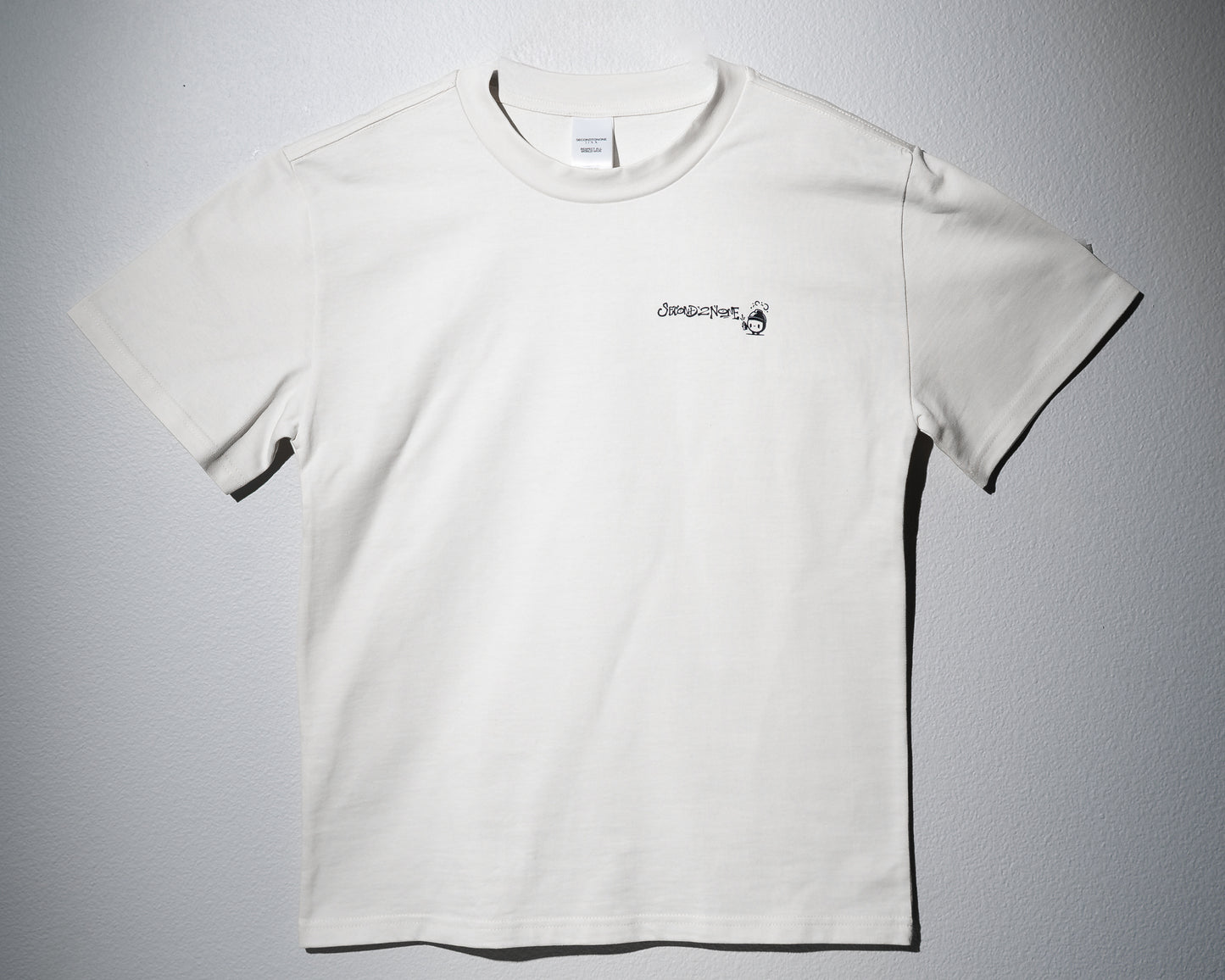 a heavyweight tee in white with a left chest graphic of the second to none logo in graffiti type