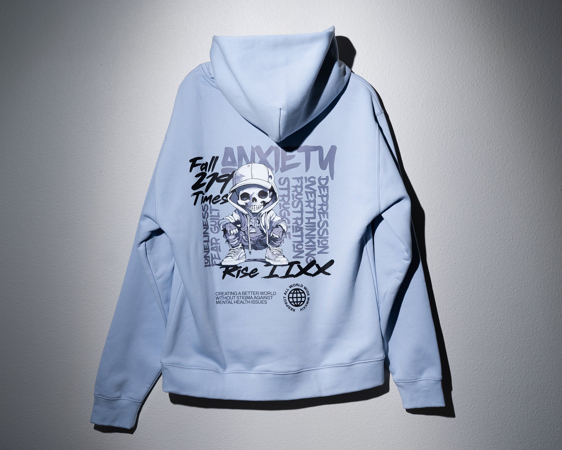 a powder blue midweight hoodie with a large graphic on the back that has words of mental health struggles as well as a skeleton character wearing streetwear