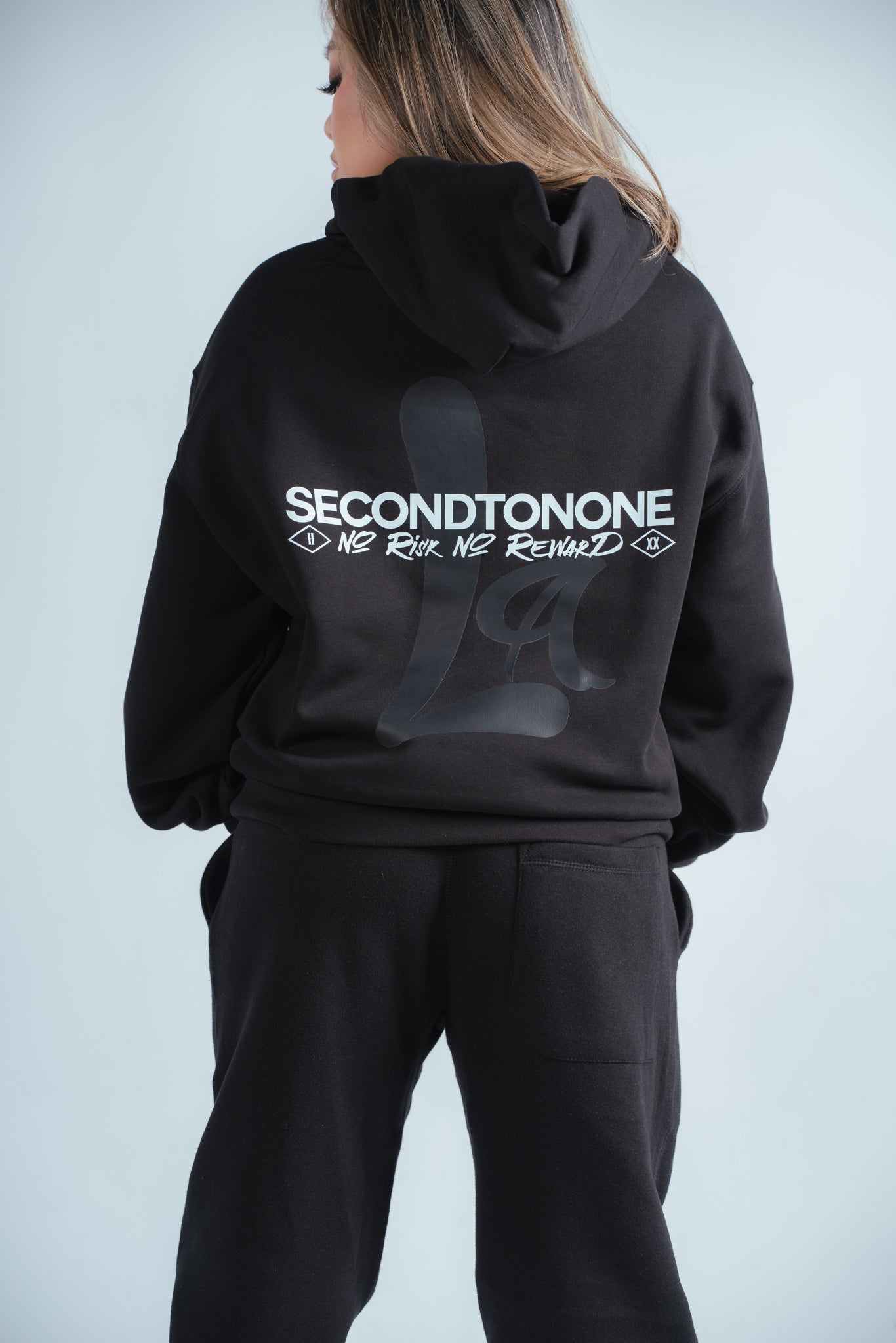 female model showing the back of the no risk relaxed hoodie graphic