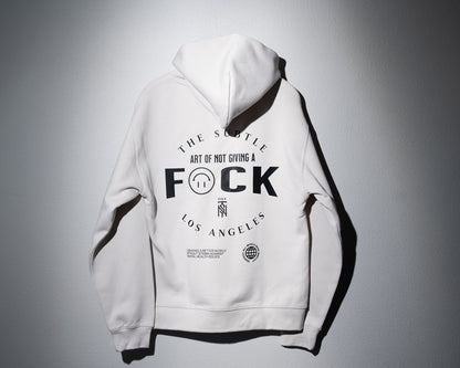 a midweight hoodie in bone color with a large graphic on the back that says the subtle art of not giving a f-word with an upside down happy face substituting the U to avoid using the derogatory word