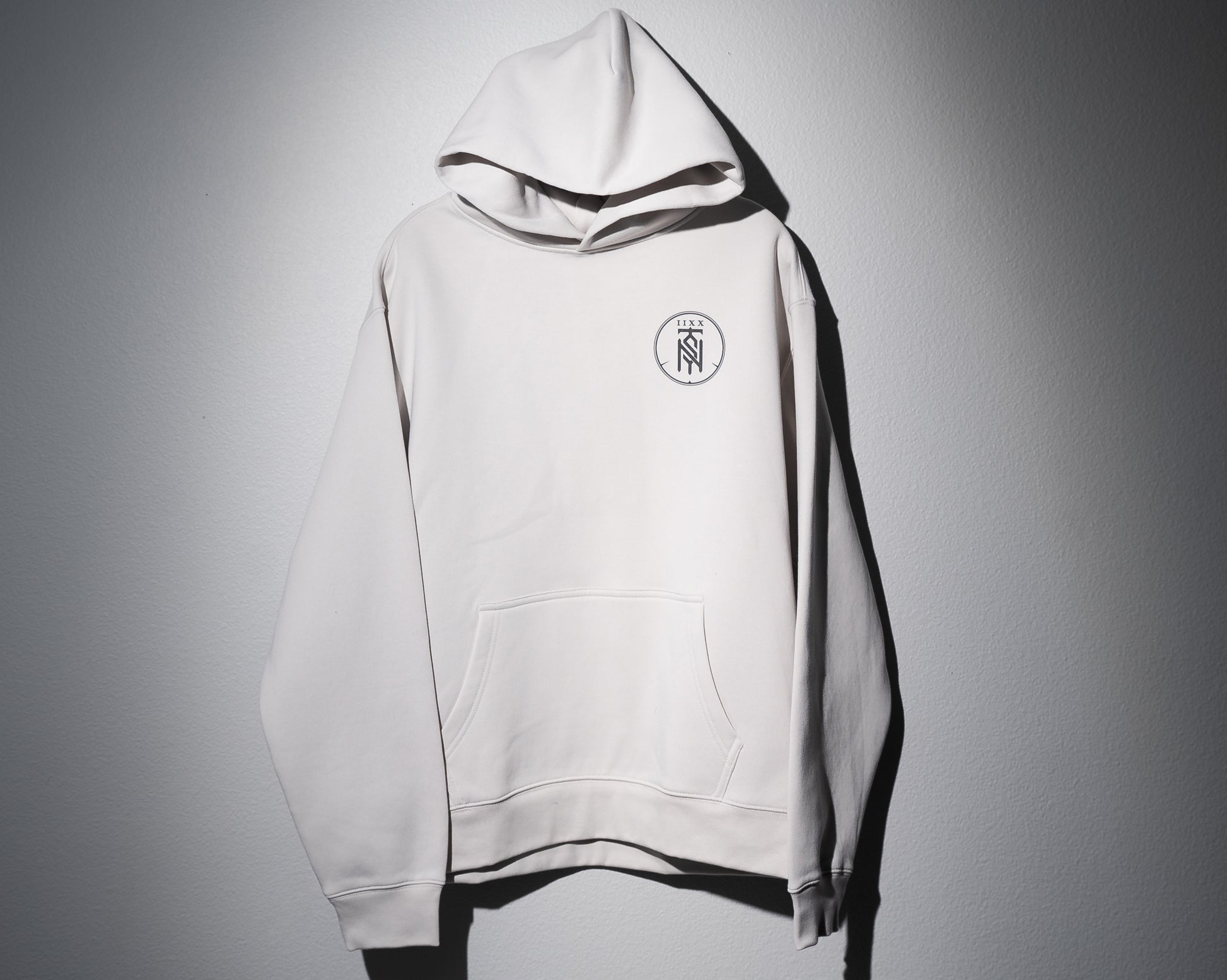 the front of a bone colored midweight hoodie with the second to none monogram printed on the left chest